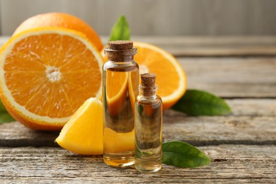 Essential oils in bottles, oranges and green leaves on wooden table