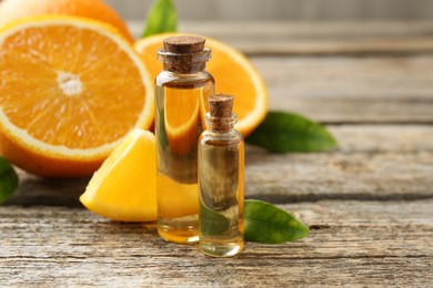 Essential oils in bottles, oranges and green leaves on wooden table