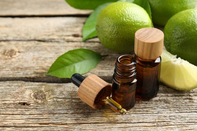 Photo of Essential oils in bottles, dropper, limes and green leaves on wooden table