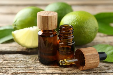 Essential oils in bottles, dropper, limes and green leaves on wooden table, closeup