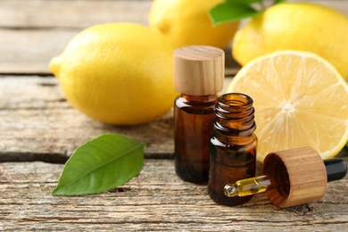 Photo of Essential oils in bottles, dropper, lemons and green leaves on wooden table