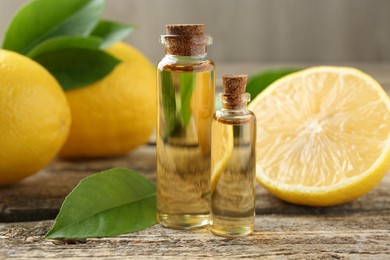 Photo of Essential oils in bottles, lemons and green leaves on wooden table, closeup