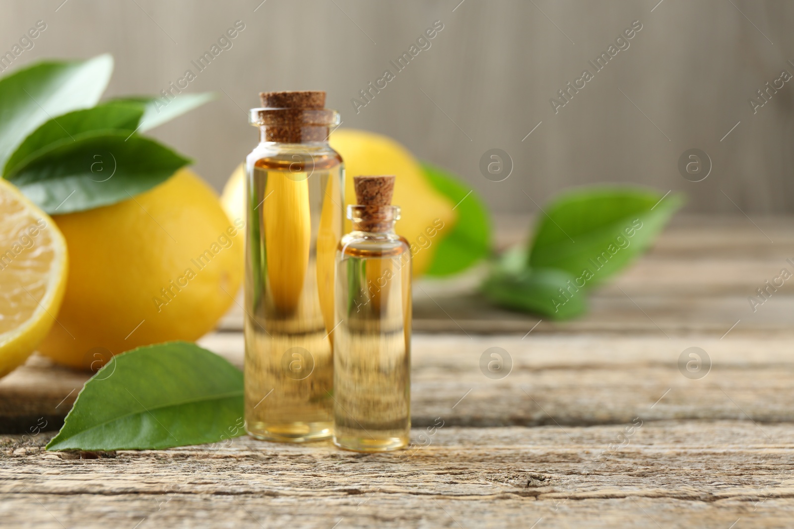 Photo of Essential oils in bottles, lemons and green leaves on wooden table, space for text