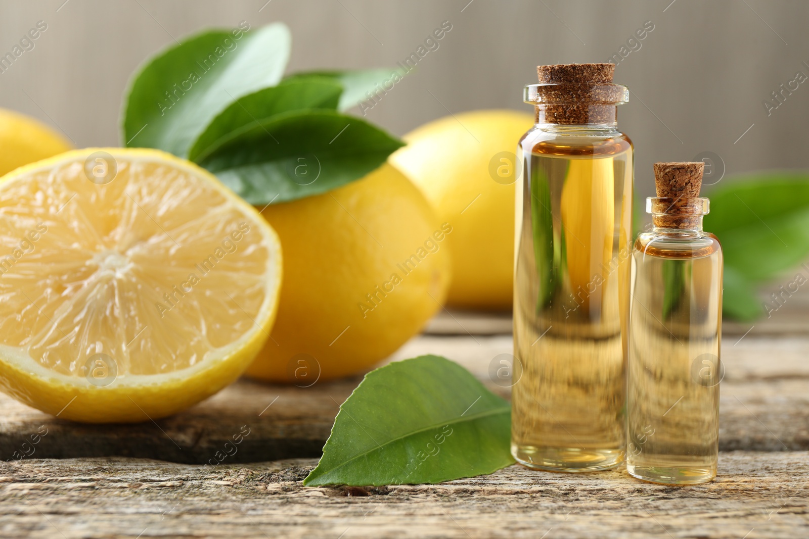 Photo of Essential oils in bottles, lemons and green leaves on wooden table, closeup