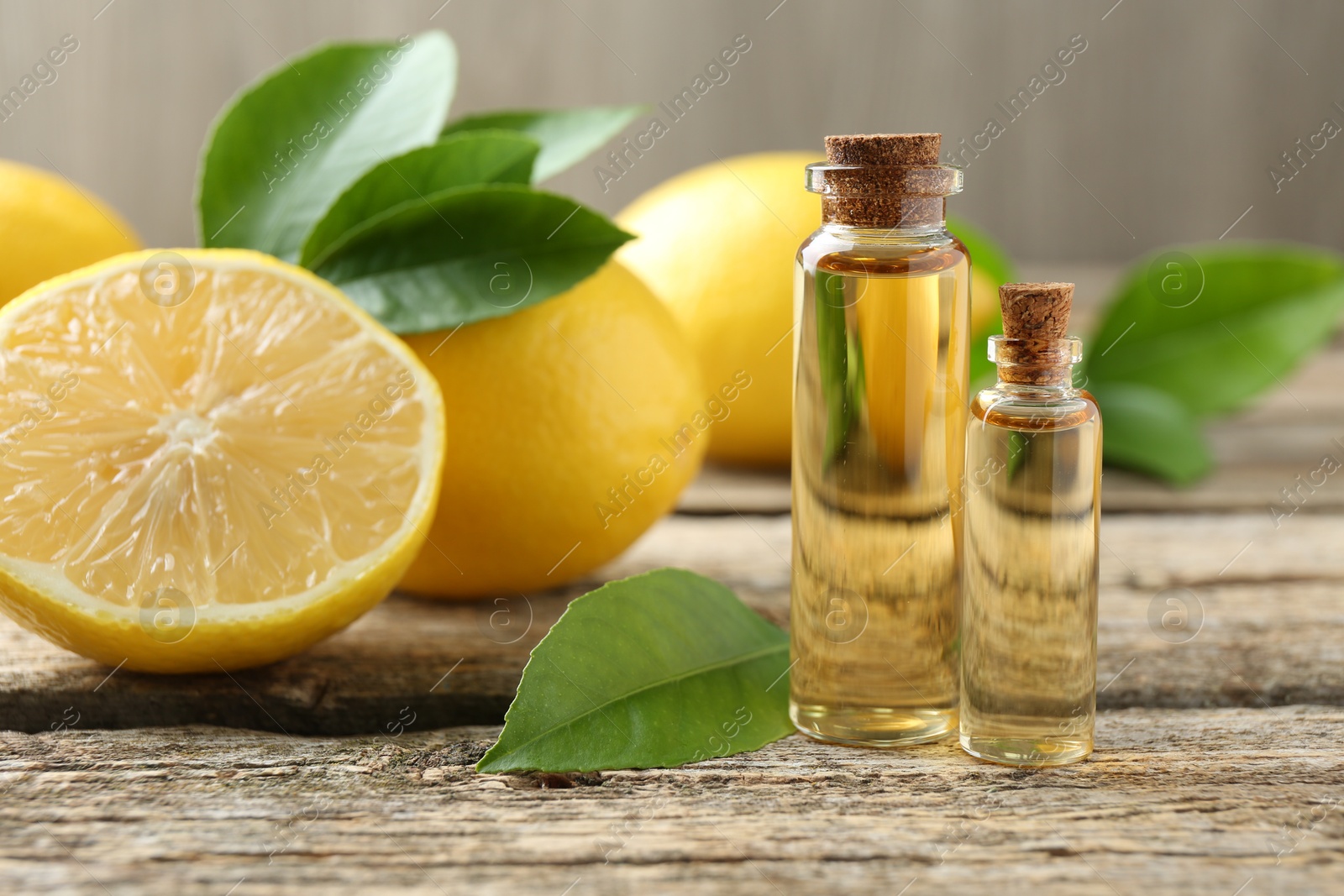 Photo of Essential oils in bottles, lemons and green leaves on wooden table