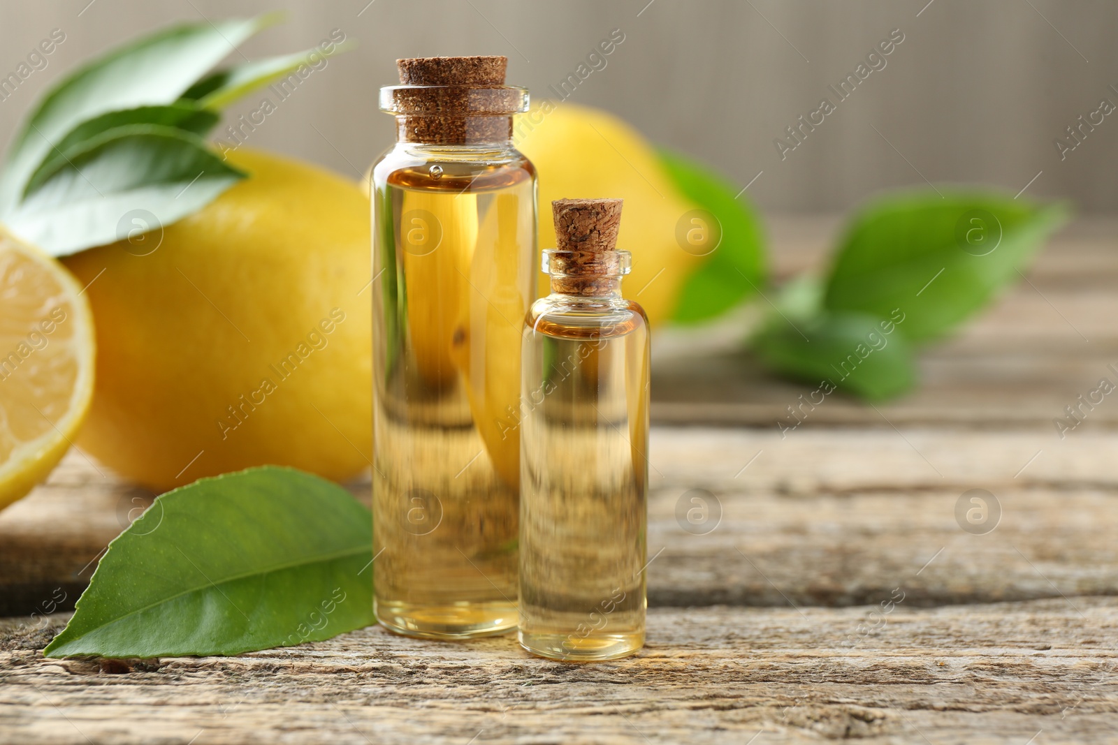 Photo of Essential oils in bottles, lemons and green leaves on wooden table, closeup. Space for text