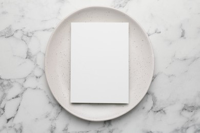 Photo of Empty menu and plate on white marble table, top view. Mockup for design