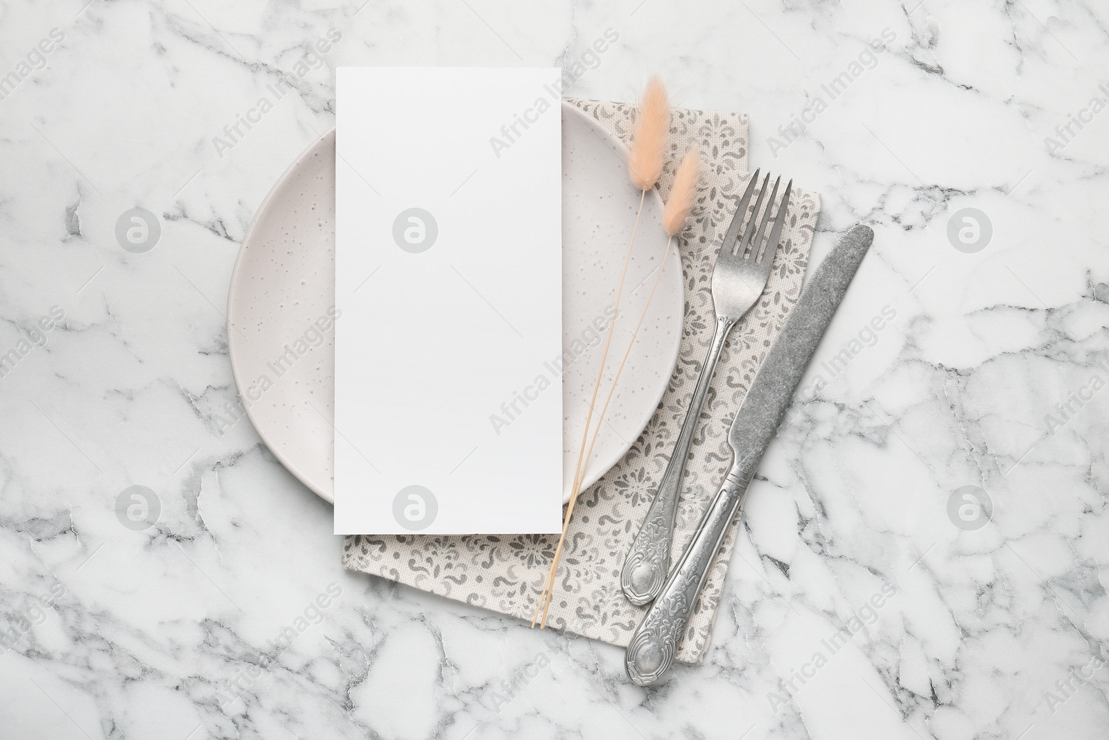 Photo of Empty menu, cutlery, plate, napkin and dry spikes on white marble table, top view. Mockup for design