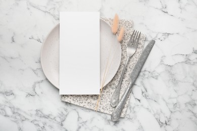 Empty menu, cutlery, plate, napkin and dry spikes on white marble table, top view. Mockup for design