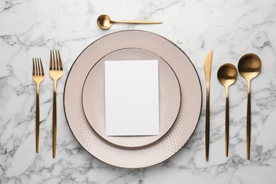 Photo of Empty menu, cutlery and plates on white marble table, flat lay. Mockup for design