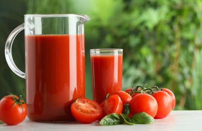 Photo of Tasty tomato juice, basil and fresh vegetables on white table outdoors