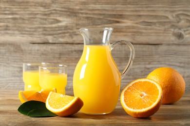 Photo of Tasty orange juice, fresh fruits and green leaf on wooden table