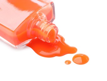 Photo of Bottle and spilled orange nail polish isolated on white