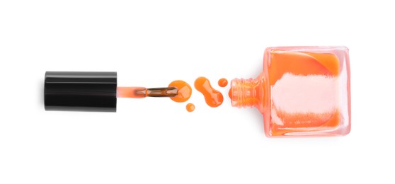 Photo of Bottle, brush and spilled orange nail polish isolated on white, top view