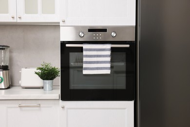 Electric oven with striped towel in kitchen. Cooking appliance