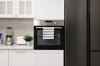 Electric oven with striped towel in kitchen. Cooking appliance