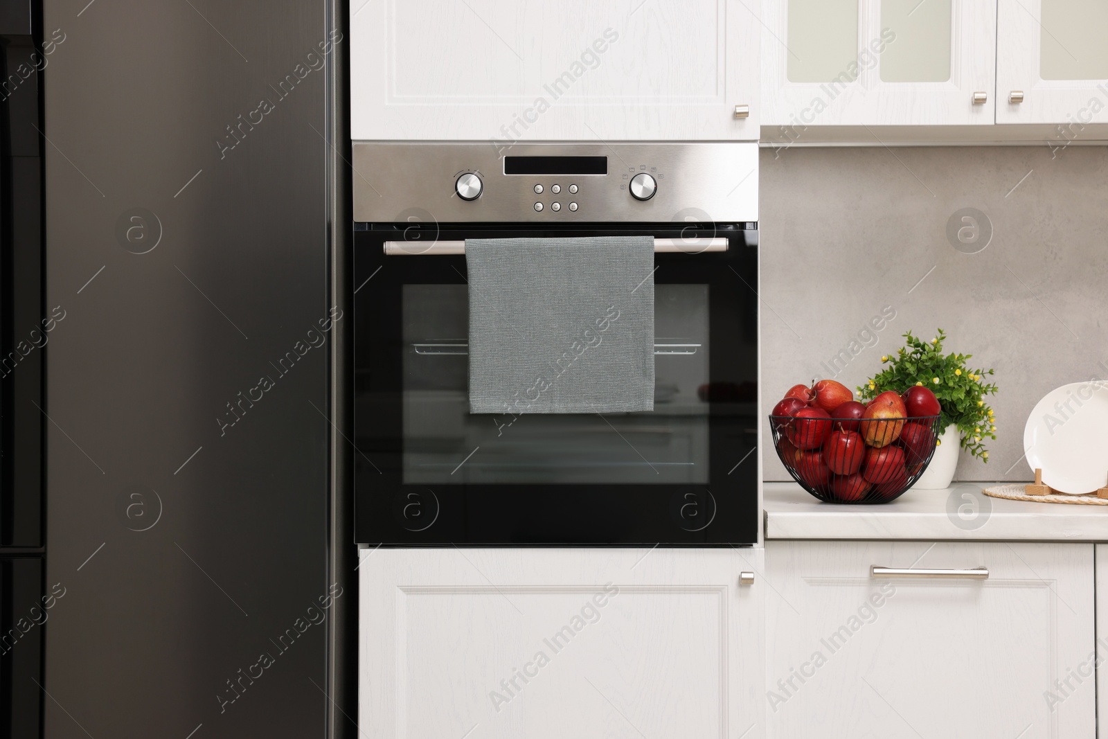 Photo of Electric oven with towel in kitchen. Cooking appliance