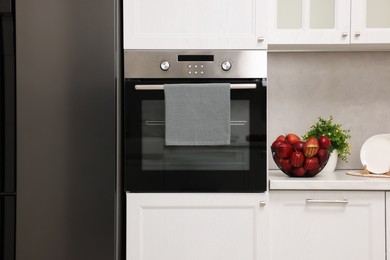 Photo of Electric oven with towel in kitchen. Cooking appliance