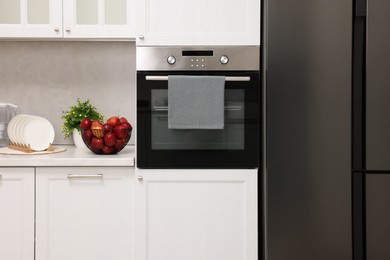 Photo of Electric oven with towel in kitchen. Cooking appliance