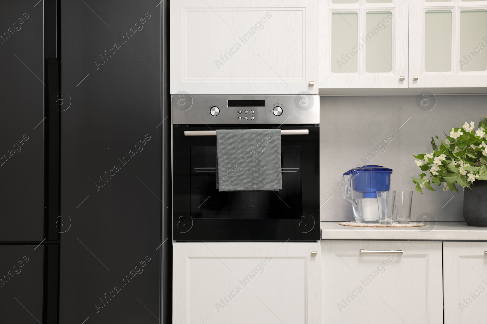 Photo of Electric oven with towel in kitchen. Cooking appliance