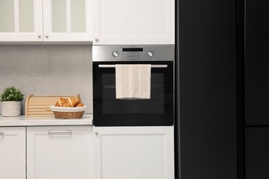 Electric oven with towel and croissants in kitchen. Cooking appliance