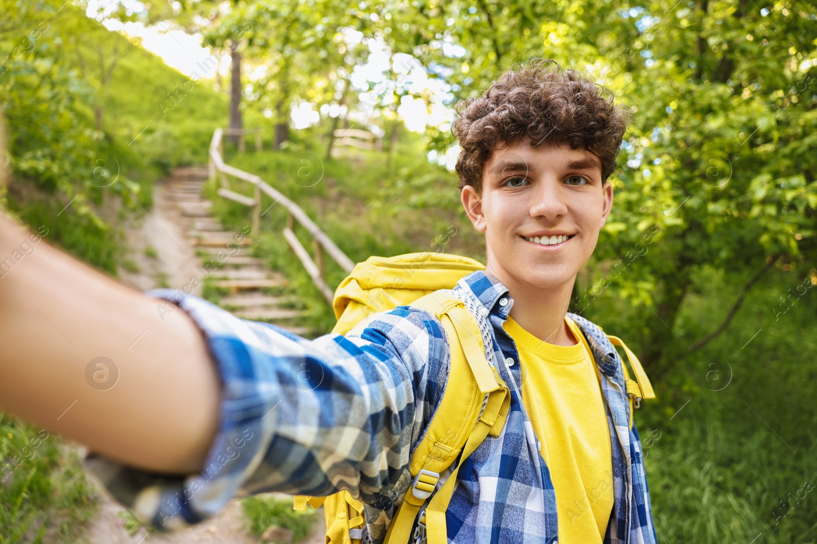 Photo of Smiling travel blogger with backpack takIng selfie outdoors