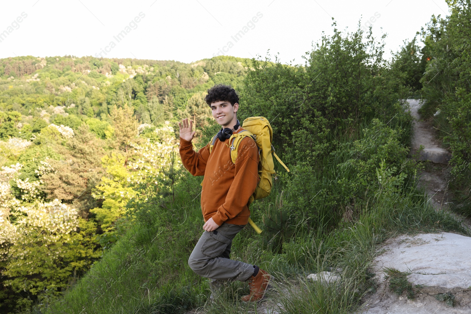 Photo of Travel blogger with headphones and backpack recording video outdoors