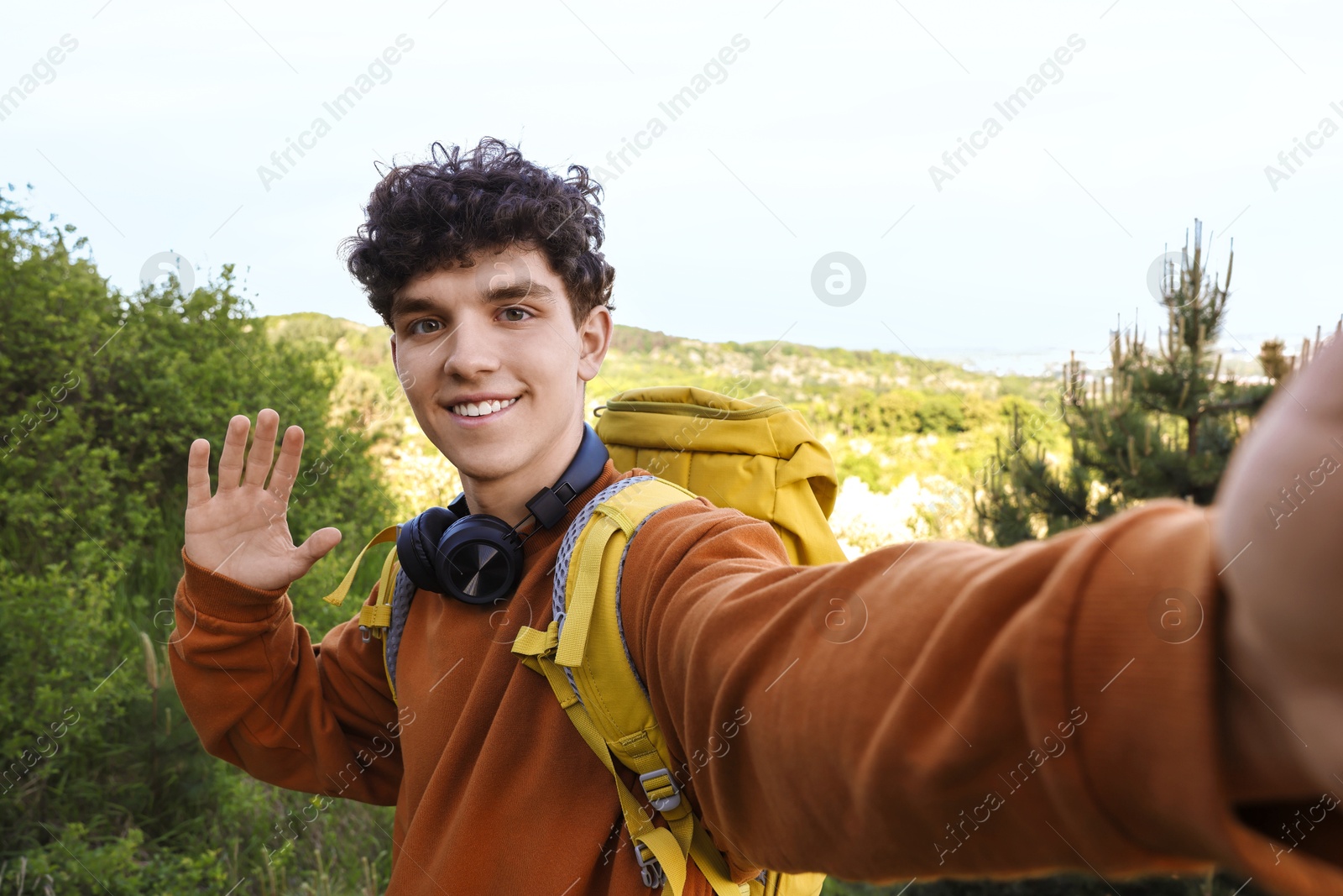 Photo of Travel blogger with headphones takIng selfie outdoors