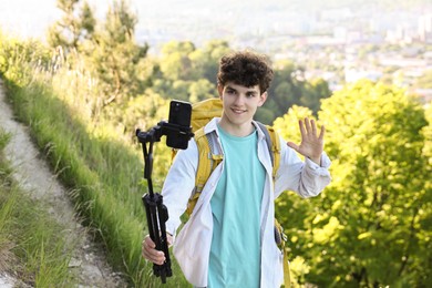 Travel blogger with smartphone and tripod streaming outdoors