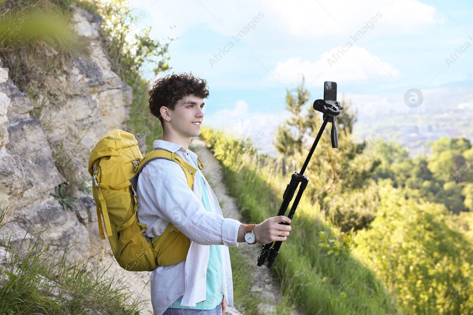 Photo of Travel blogger with smartphone and tripod recording video outdoors