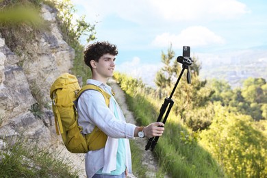 Travel blogger with smartphone and tripod recording video outdoors