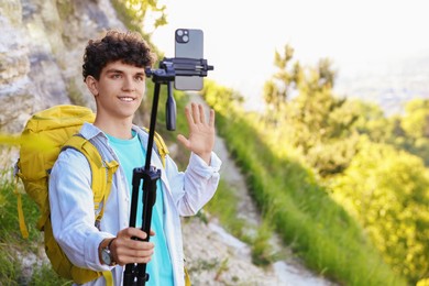 Travel blogger with smartphone and tripod streaming outdoors, space for text