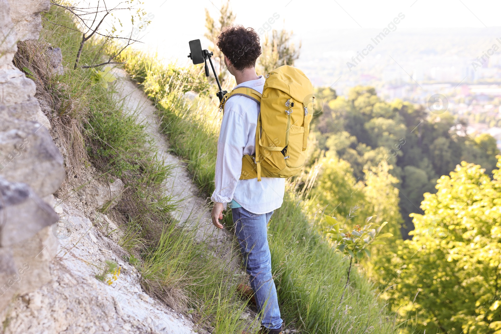 Photo of Travel blogger with smartphone and tripod recording video outdoors