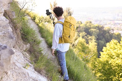 Photo of Travel blogger with smartphone and tripod recording video outdoors