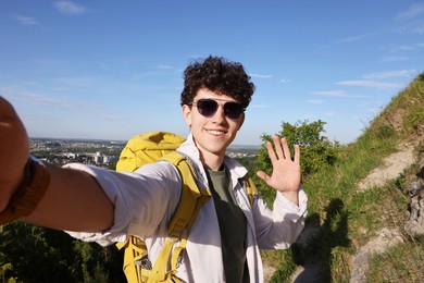 Happy travel blogger in sunglasses streaming outdoors