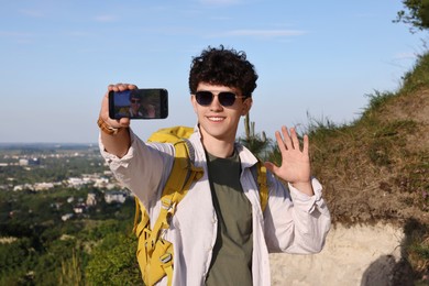 Travel blogger in sunglasses with smartphone streaming outdoors