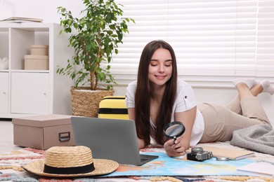 Travel blogger with magnifying glass and map planning trip at home