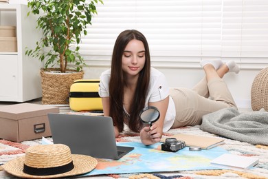 Travel blogger with magnifying glass and map planning trip at home