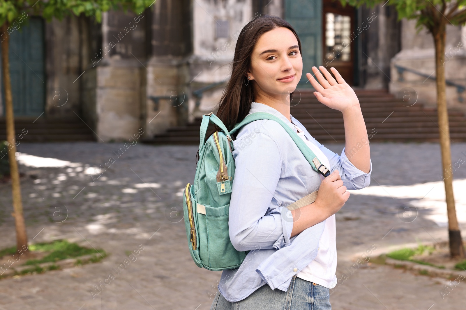 Photo of Travel blogger with backpack recording video on city street