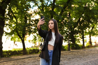 Photo of Travel blogger takIng selfie with smartphone outdoors