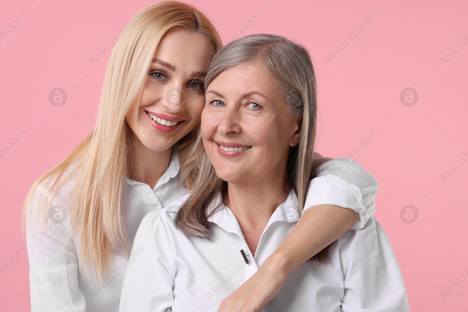 Photo of Family portrait of young woman and her mother on pink background