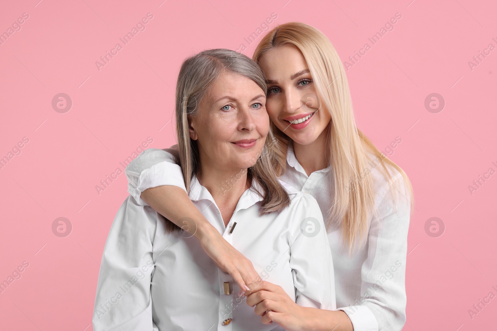 Photo of Family portrait of young woman and her mother on pink background