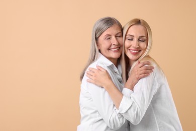 Photo of Family portrait of young woman and her mother on beige background. Space for text