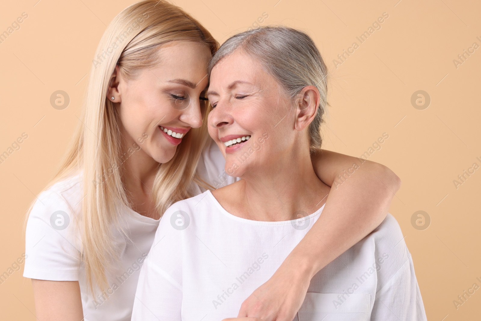 Photo of Family portrait of young woman and her mother on beige background