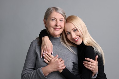 Photo of Family portrait of young woman and her mother on grey background