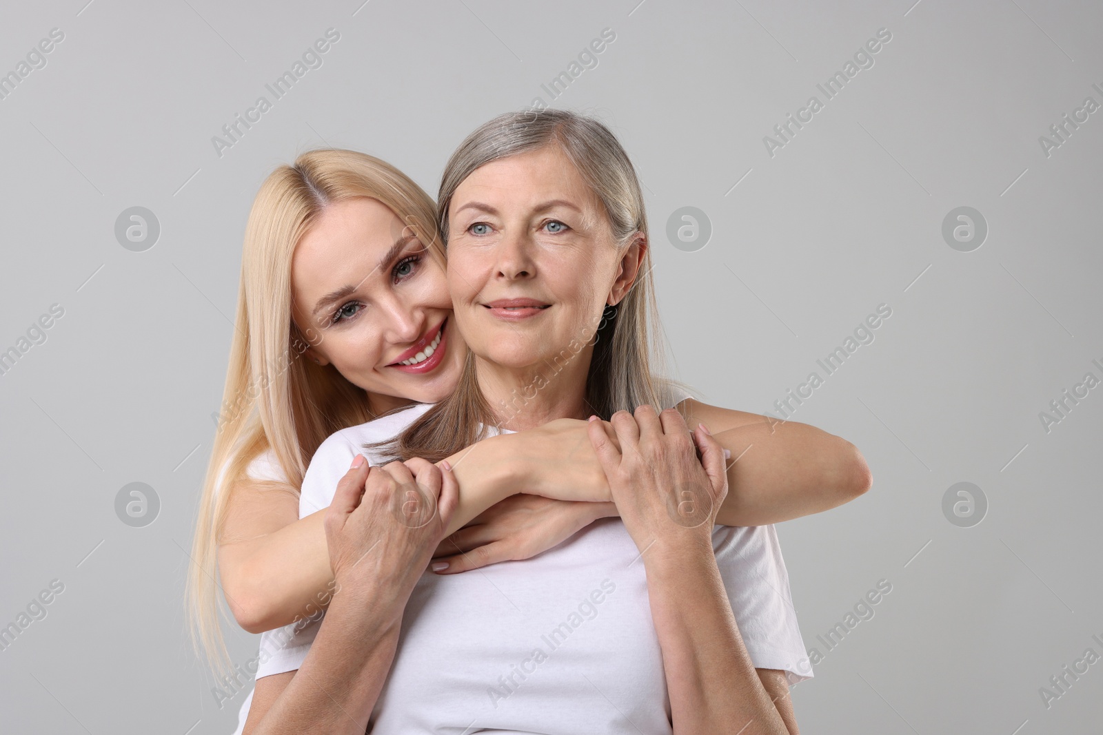 Photo of Family portrait of young woman and her mother on light grey background