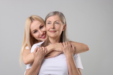 Photo of Family portrait of young woman and her mother on light grey background