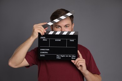 Making movie. Man with clapperboard on grey background