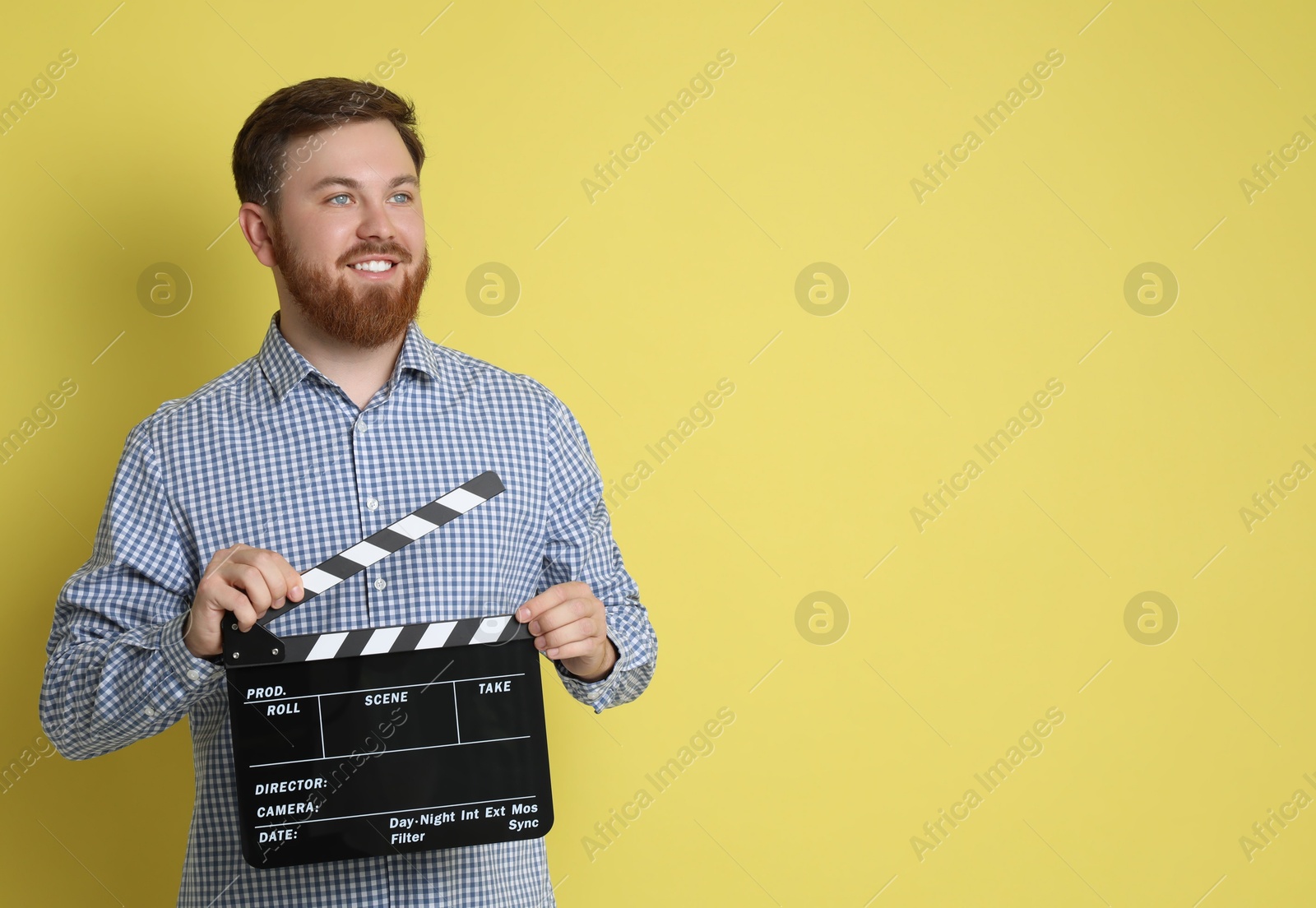 Photo of Making movie. Smiling man with clapperboard on yellow background. Space for text
