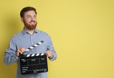 Making movie. Smiling man with clapperboard on yellow background. Space for text